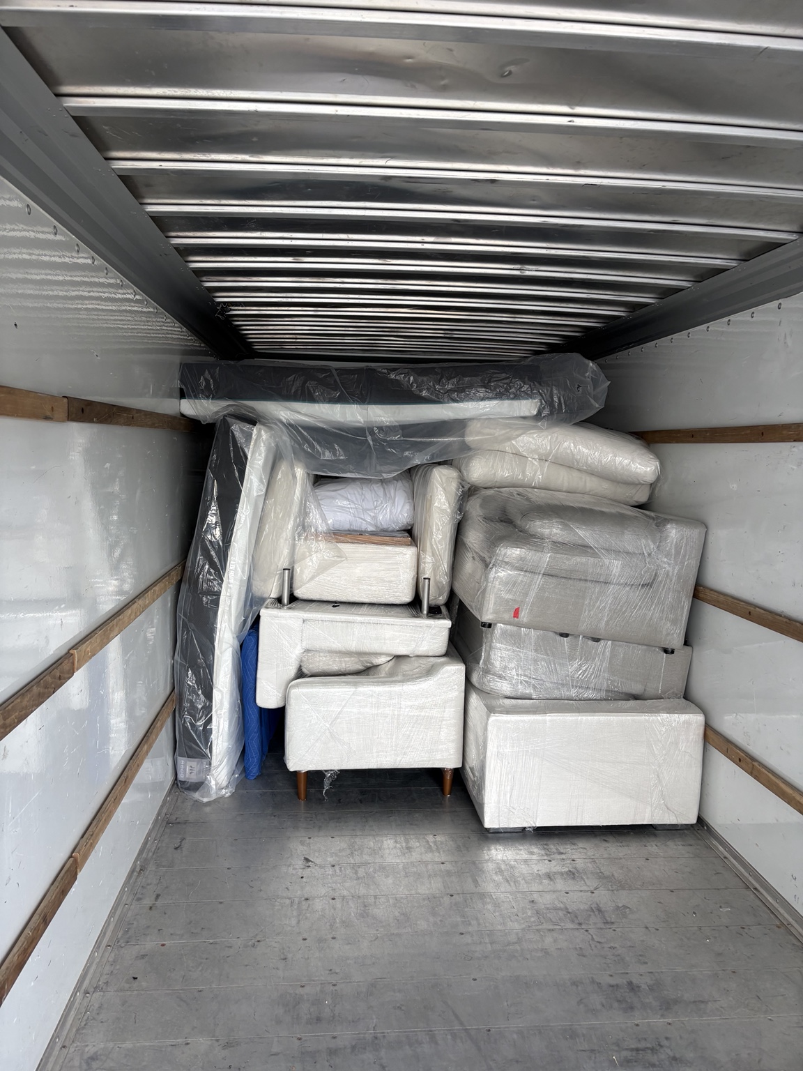 Wrapped sofas and armchairs packed at the front of the moving truck