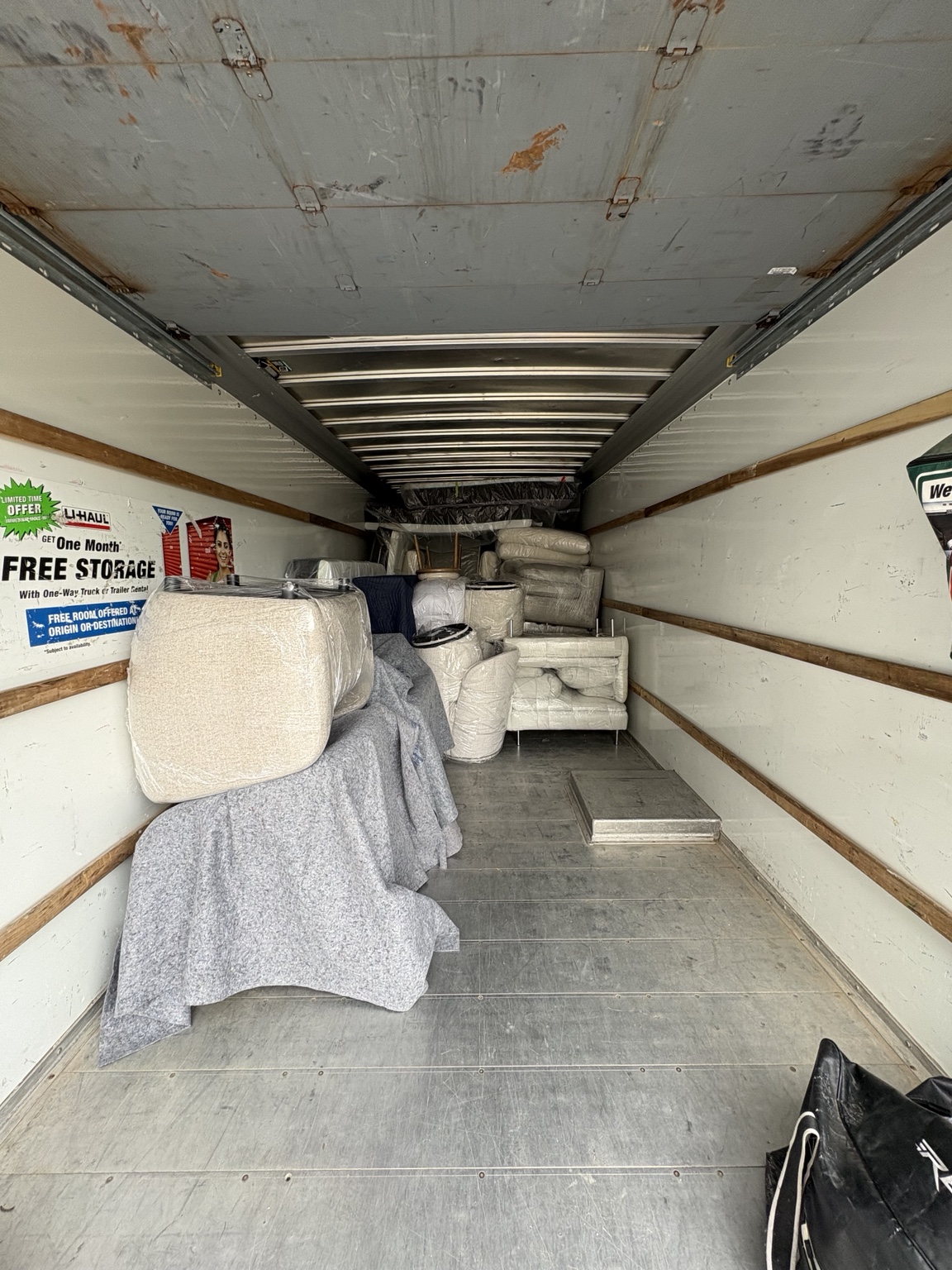 Additional wrapped seating and blanket-covered furniture loaded into the truck