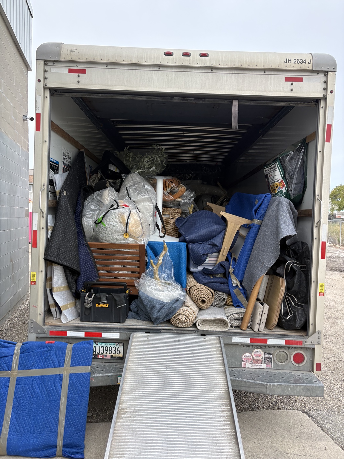Full staging load with wrapped furniture, rolled rugs, décor and moving blankets